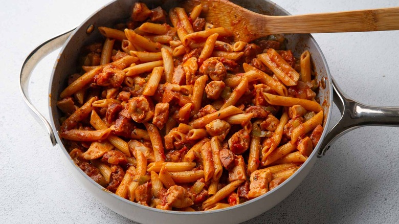pasta, tomato sauce, and a wooden spatula in a pan
