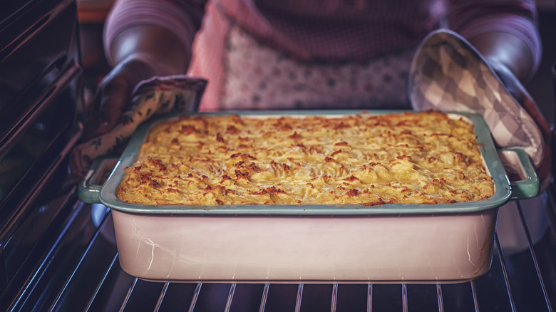 a casserole in a dish being taken out of the oven