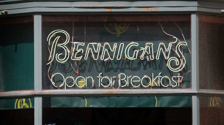 A sign reads "Bennigan's: Open for breakfast" in a store window