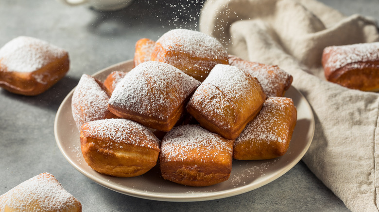 A plate of powdered sugar dusted beignets