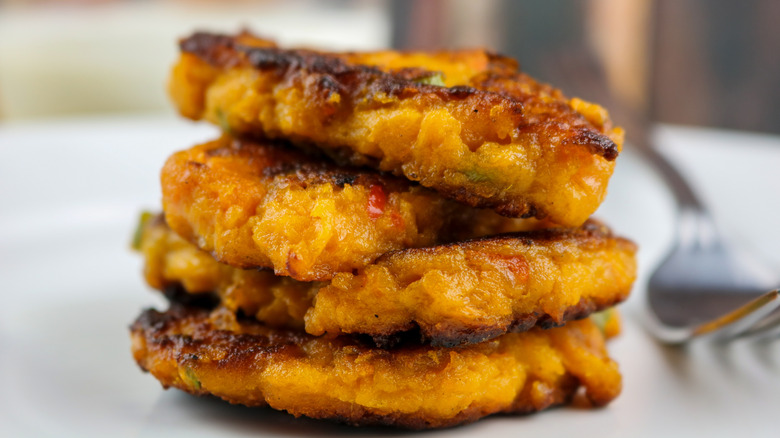 A stack of sweet potato pancakes drizzled with syrup