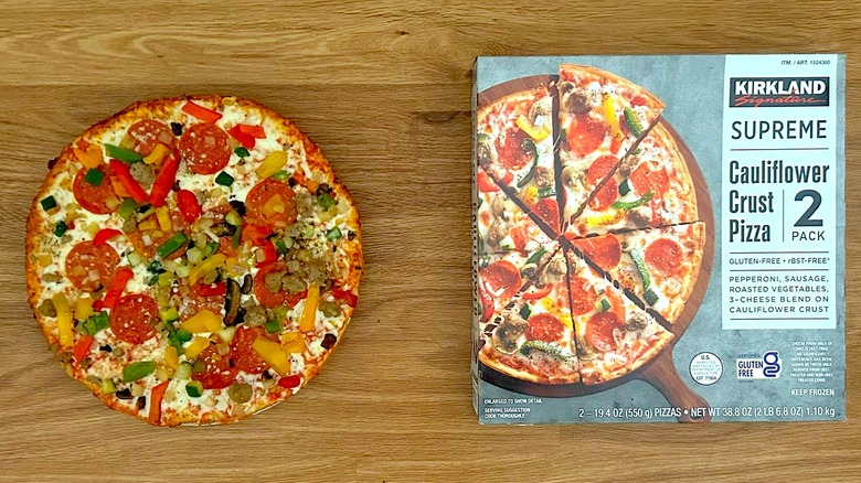Package and baked Kirkland Signature Cauliflower Crust Pizza, Supreme on round plate