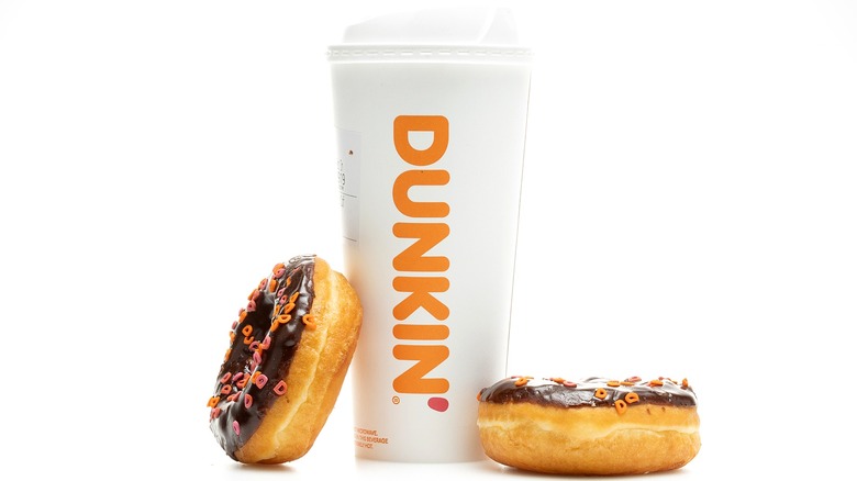 A cup of Dunkin' coffee with two donuts