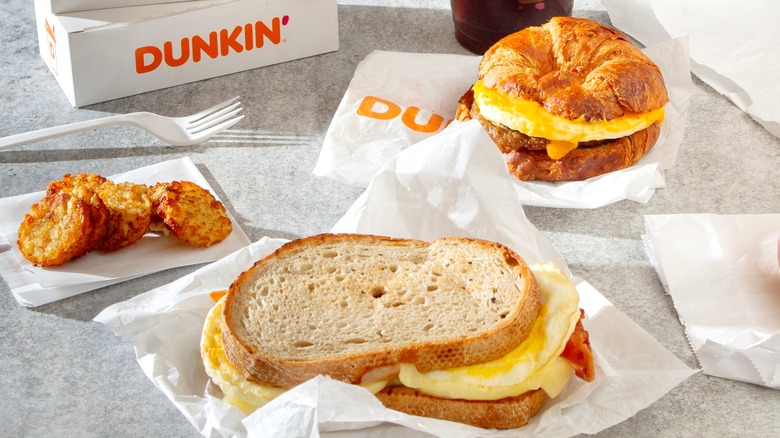 A Dunkin' breakfast spread with two sandwiches and hashbrowns