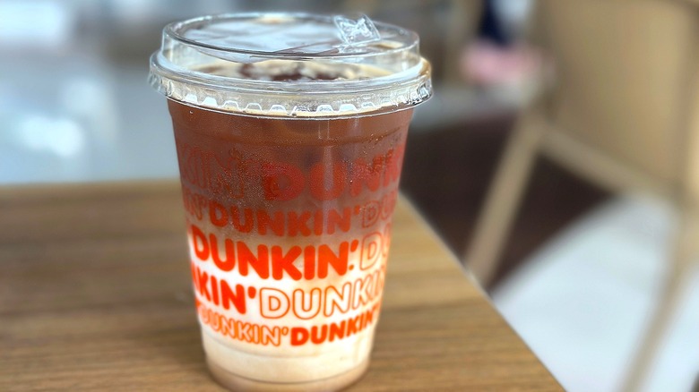 A Dunkin' iced coffee drink on a wooden table