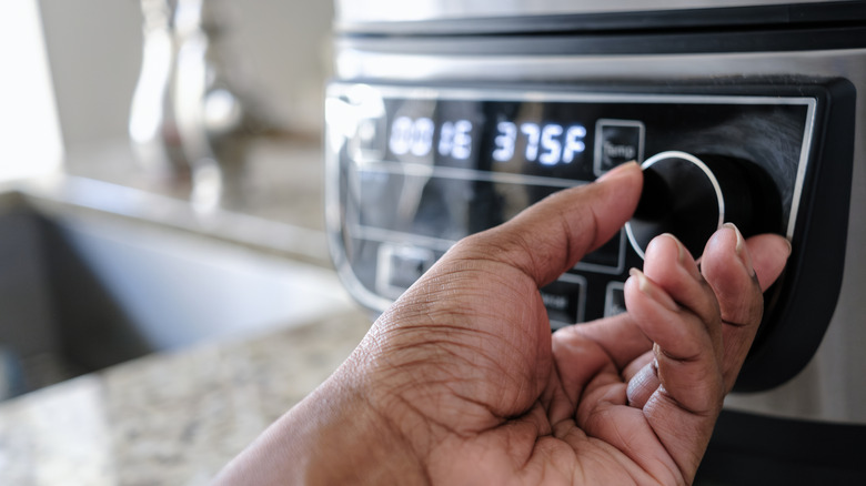 Person adjusting an air fryer's temperature