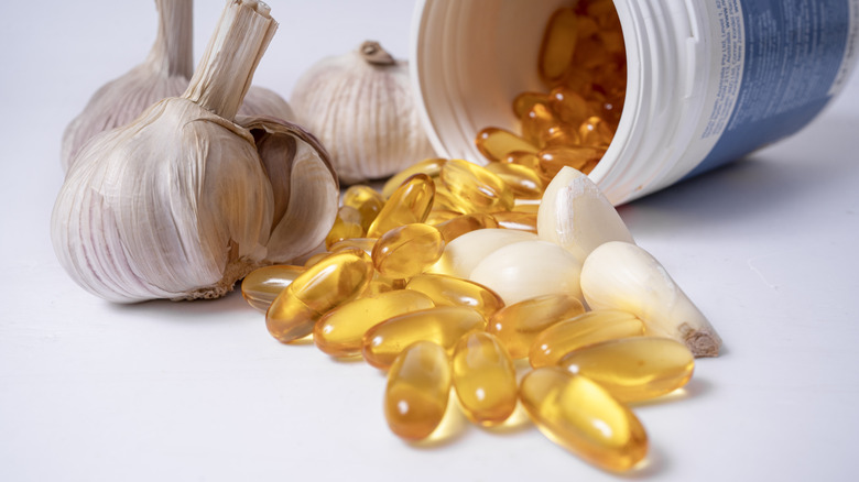 Garlic supplement capsules next to garlic cloves