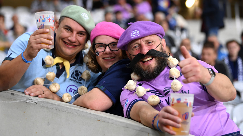 Three people at a festival wearing garlic necklaces