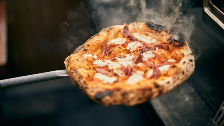 Burnt pizza being pulled from the oven