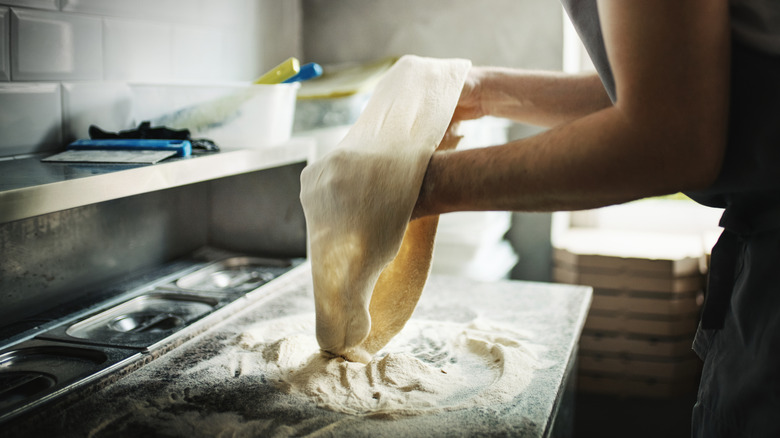 A person stretching pizza dough
