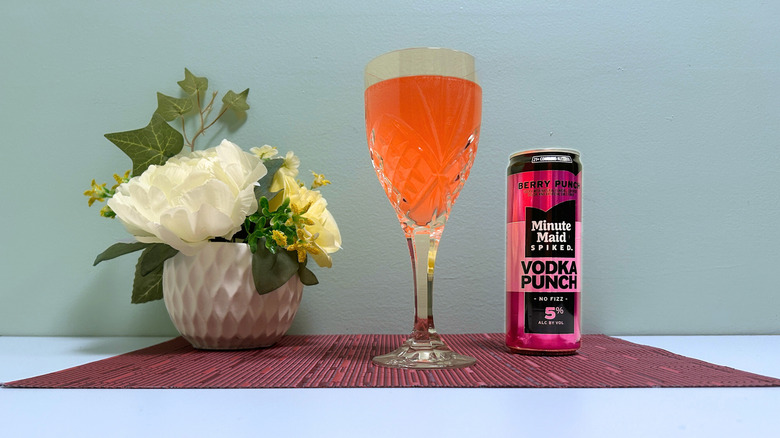 A can of Minute Maid Spiked Berry Punch next to a glass of orange liquor on a blue background