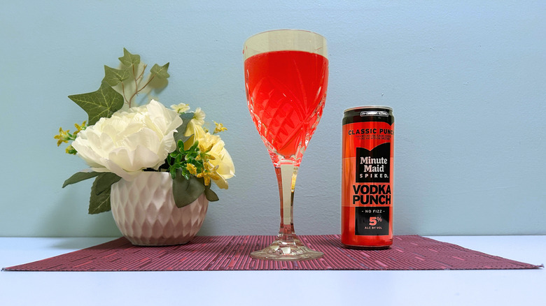 A can of Minute Maid Spiked Vodka Punch next to a glass of red liquor on a blue background