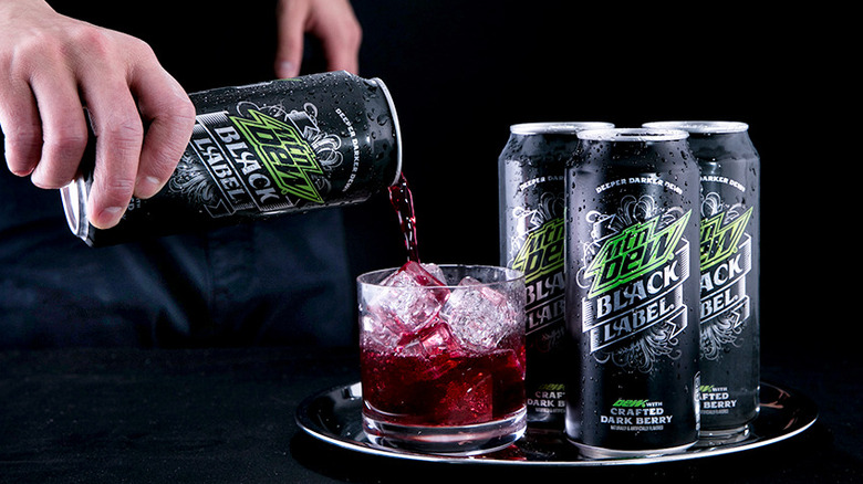 Cans of Mountain Dew Black Label being poured into a glass with ice