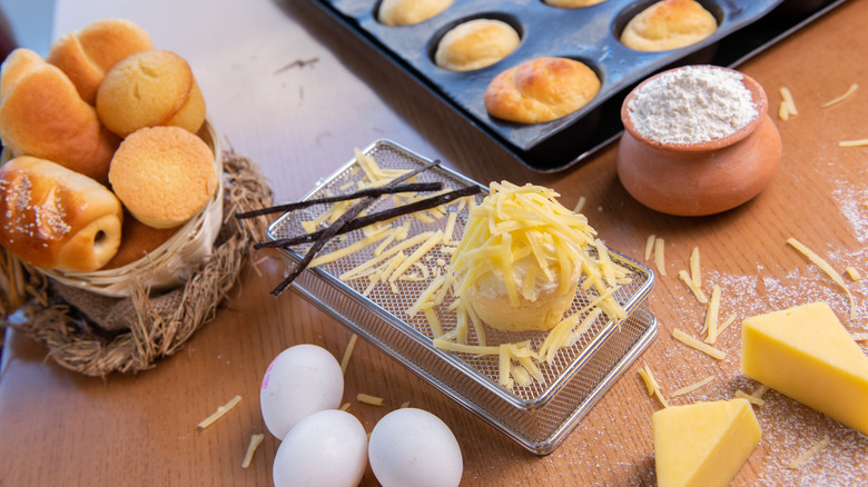 Ensaymada being prepared on a table, with eggs, flour, and cheese.