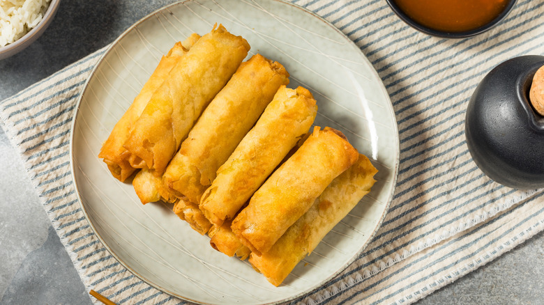 A plate full of filipino lumpia set on a table