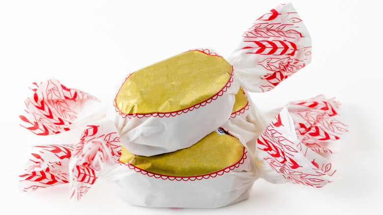 Stack of polvoron wrapped in festive paper with red and gold decoration..