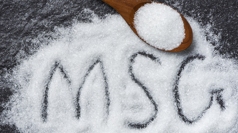 MSG spread on a black table with MSG written within it along with a wooden spoon