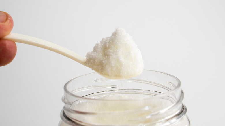 A person taking out a spoonful of MSG from a jar