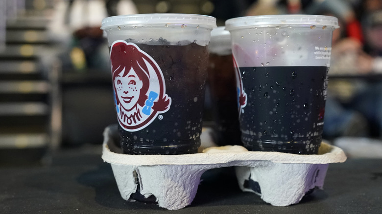 Four sodas in Wendy's drink cups, in a drink holder.