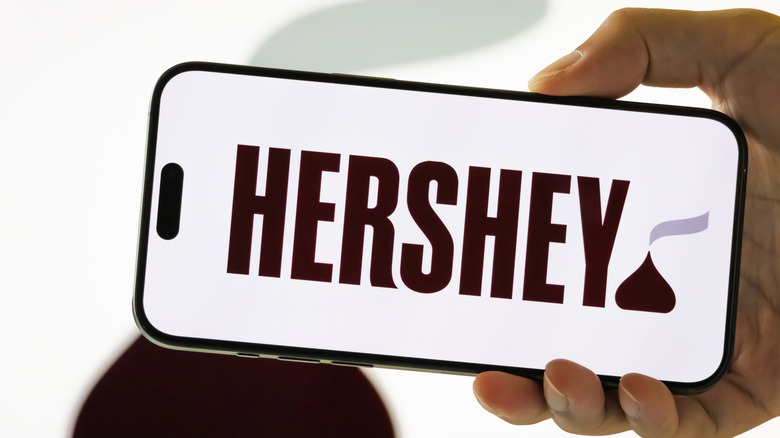A hand holding an iphone with the new hershey logo on the screen.