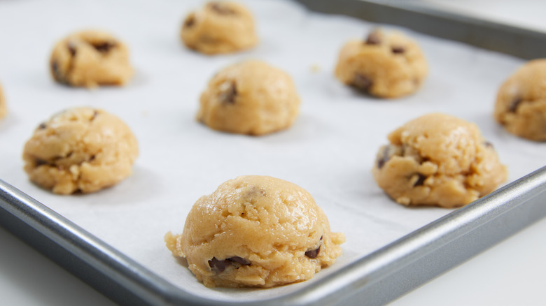 Raw cookie dough on a baking sheet with parchment paper