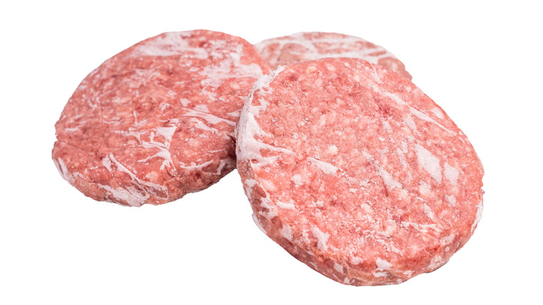 Three frozen hamburger patties on a white background