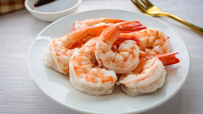 A plate of cooked and peeled shrimp on a white plate