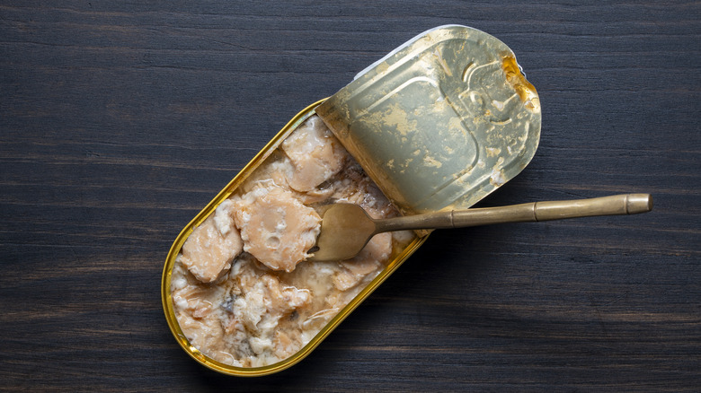 A can of salmon opened on a table with a fork inside
