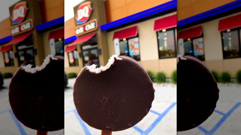 Dilly bar held up in front of DQ restaurant