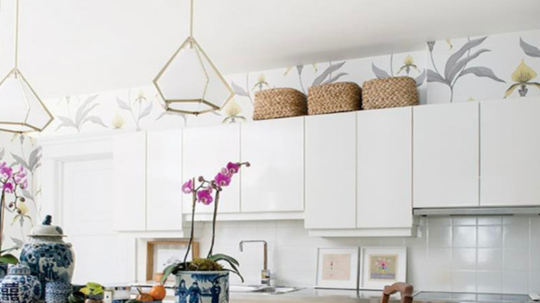 White kitchen with floral wallpaper above cabinets
