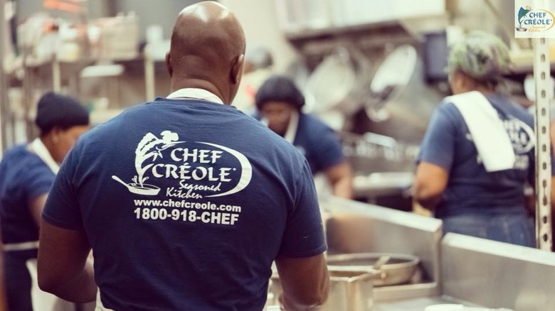 A man in a blue Chef Creole t shirt works in the kitchen.