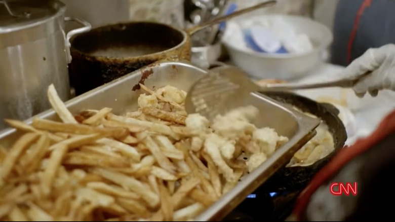 A pan of french fries and fried shrimp over a stove with visible cast iron pans.