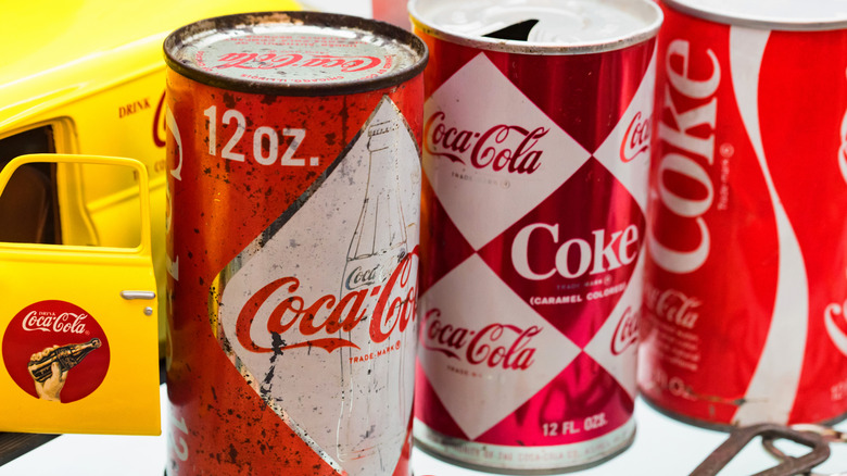 A selection of vintage Coca-Cola cans, including a very old can with no ring pull.