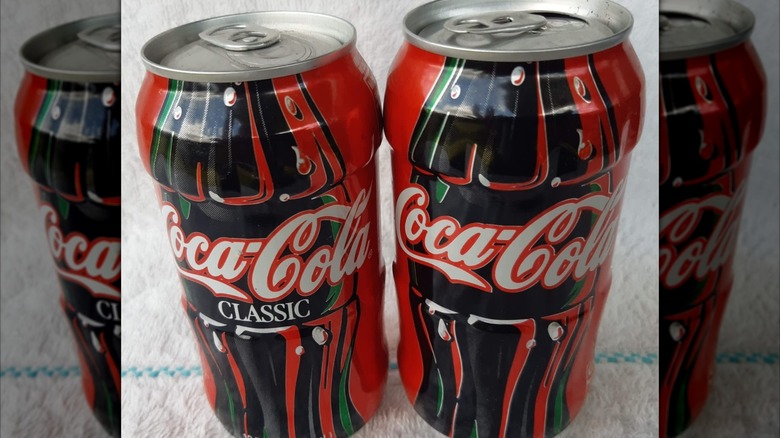 Two vintage Coca-Cola contour cans, showing their distinctive shape.