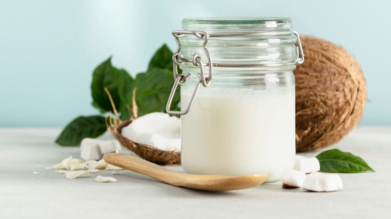 Jar of coconut oil with fresh coconut in the background