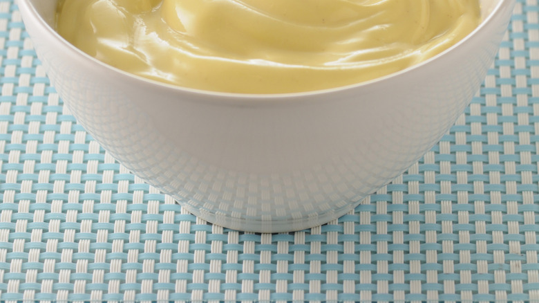 Bowl of mayo with eggs and lemon in the background
