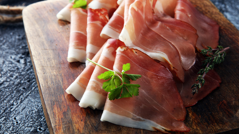Thinly sliced prosciutto on cutting board