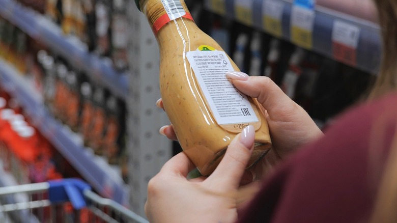 salad dressing held by a woman in a grocery store