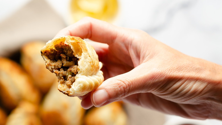 A woman holding a delicous canned roast beef spread empanada