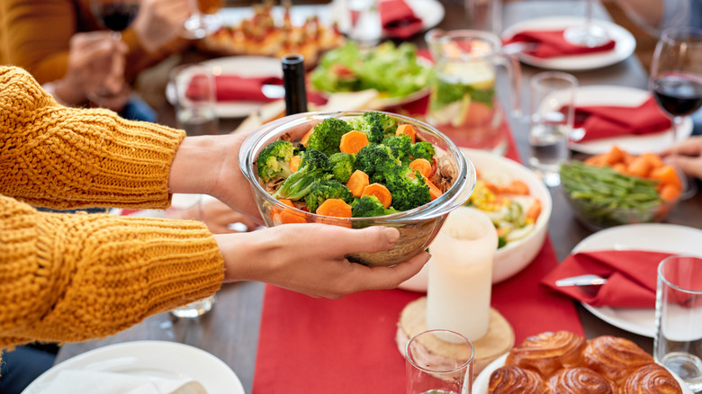 Person holding vegetables over dinner table