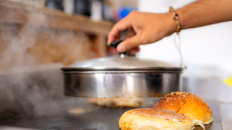 A heat dome being placed over the top of a cheeseburger
