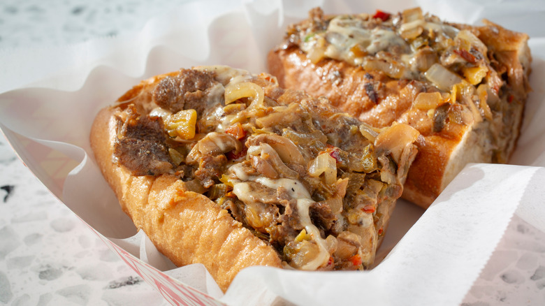 A cheesecake cut in half with steak, onions, peppers, and melted cheese