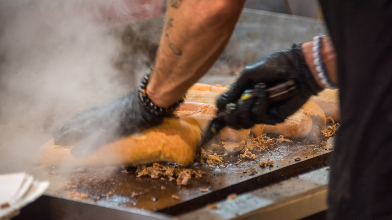 A chef flipping a cheesesteak sandwich before serving