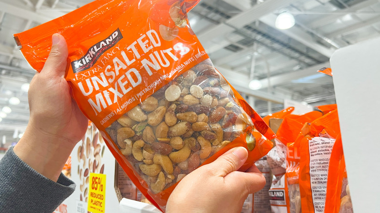 Person holding a bag of Kirkland Signature extra fancy unsalted mixed nuts in store