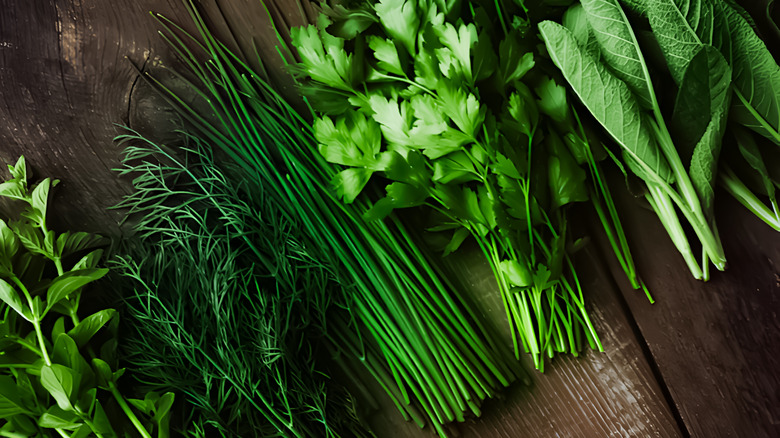 Fresh herbs inluding basil, dill, chives, parsley, and sage laid out on a cutting board