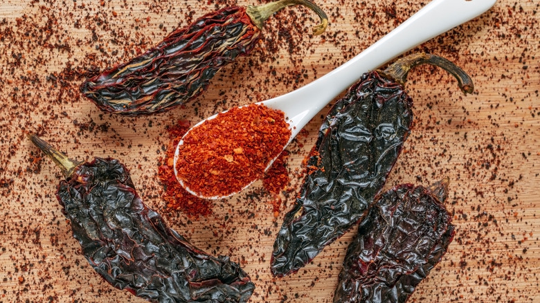 Smoked chili powder in a spoon surrounded by dried chiles