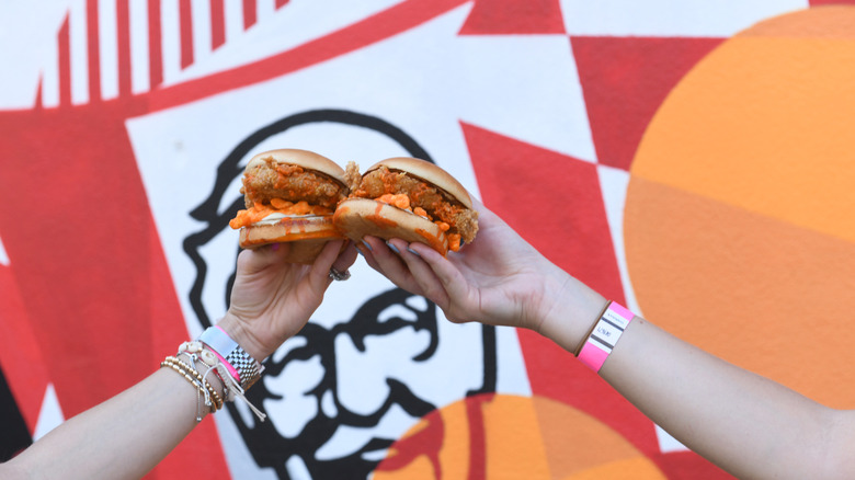 People holding two KFC Cheetos sandwiches