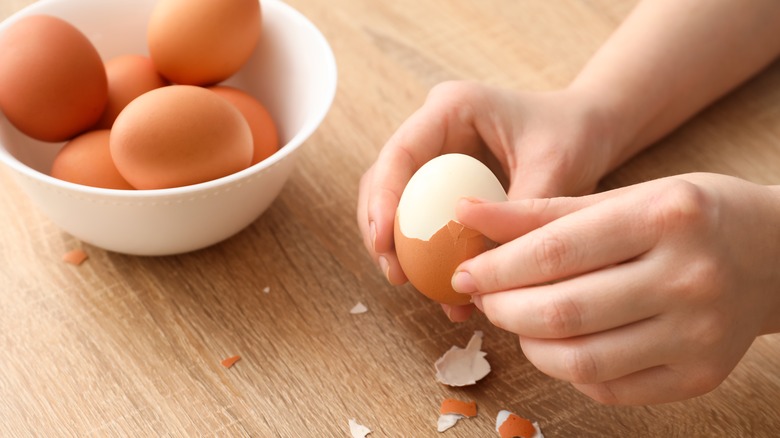 woman peeling boiled egg