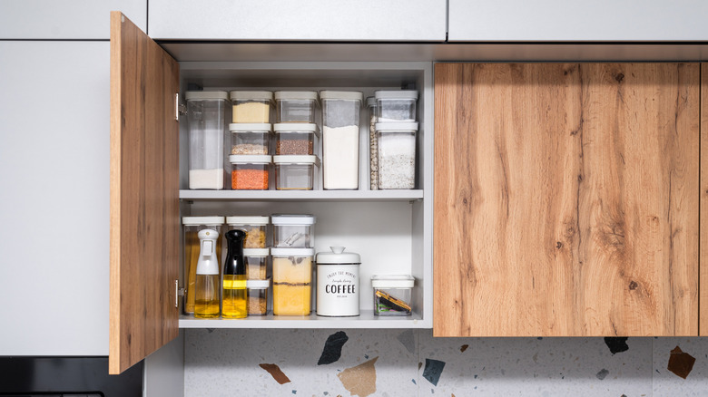 Plastic containers stacked vertically in kitchen cabinet