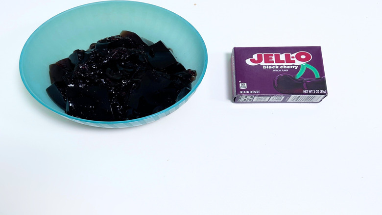 A bowl of gelatin next to a packet of Jell-O Black Cherry